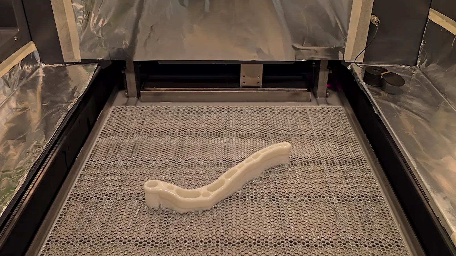 A white SLA part on the build platform, lifted out of the resin